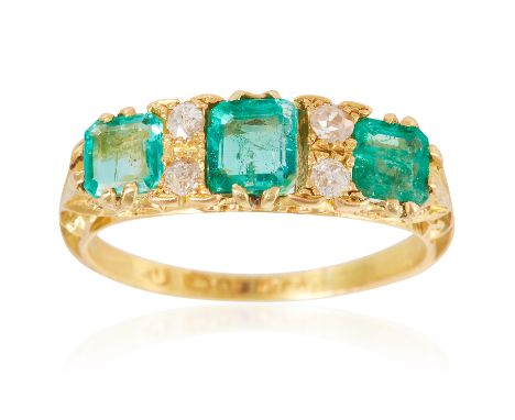 AN ANTIQUE EMERALD AND DIAMOND RING in 18ct yellow gold, the three step cut emeralds punctuated by pairs of diamonds, full Br