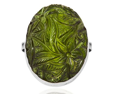 A CARVED TOURMALINE RING in platinum, set with a large, Mughal style carved green tourmaline cabochon, stamped Plat, size N /