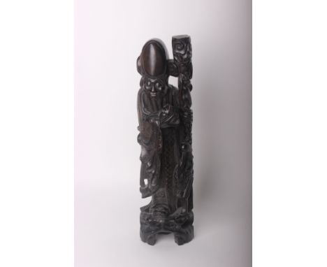 A Chinese hardwood carving of an Immortal with silver wire inlay. Lamp base, 20th century height 60cm