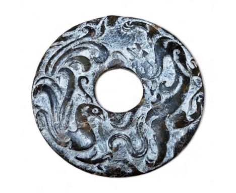 A Chinese carved calcified moss variegated jade Bi disk form carving, each side carved in relief with a ferocious dragon and 
