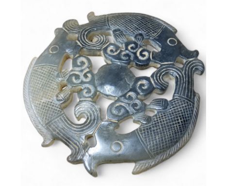 A carved Chinese spinach jade roundel, decorated with three Han Dynasty type fish, 12cm diameter