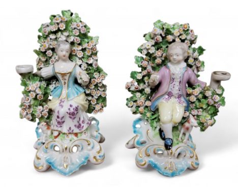 A pair of Derby Patch Mark figures, of a young gentleman and lady, he seated, wearing&nbsp; fanciful dress, dog by his side,&
