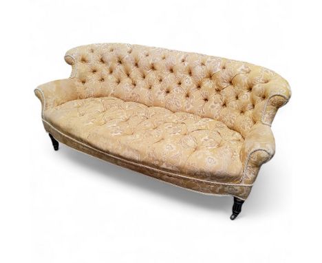 A Victorian country house button backed three-seater sofa, in gold and ivory tones, rippled damask upholstery, ebonised flute