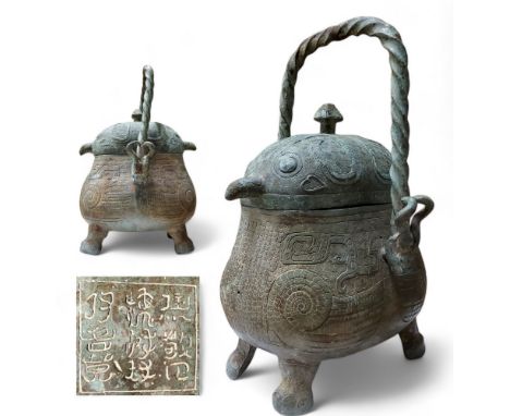 A Chinese archaic bronze wine vessel, 'Han Dynasty', rope twist swing handle terminating with mythical horned beast masks, th