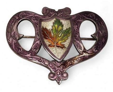 A sterling silver and enamel Art Nouveau style scrolling heart shaped brooch, the central shield depicting a maple leaf on a 