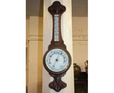A 20th century aneroid wall barometer with thermometer, in carved oak banjo shaped case, 82cm
