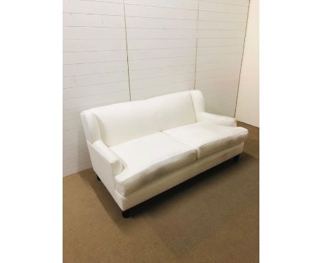 An off white two seater upholstered sofa on four bun feet designed and upholstered by Gary Andrews Upholstery (no label)