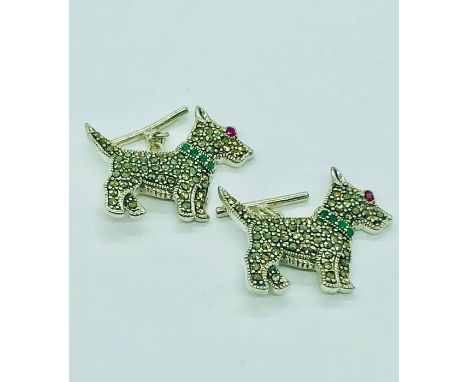 A pair of silver cufflinks in the form of dogs with emerald collar and ruby eyes.