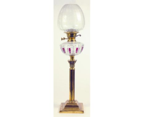 AN EDWARDIAN BRASS COLUMNAR OIL LAMP WITH RUBY FLASHED AND CUT GLASS FOUNT, BRASS BURNER AND AN ETCHED SHADE