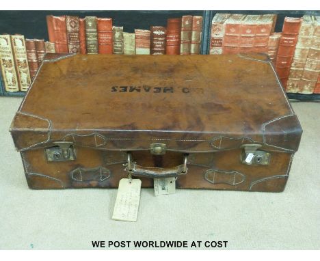 A vintage brown leather suitcase with tickets and shipping labels.