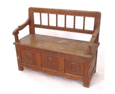 A 1920s oak hall bench, with turned spindle back, and roundel panelled front, L105cm, H86cm, D44cm, seat depth 39cm 