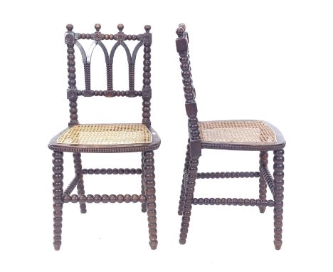 A pair of Victorian Gothic bobbin turned side chairs with caned seats