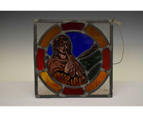 Stained and leaded glass panel depicting a figure playing a wind instrument and a village landscape, within coloured roundel 