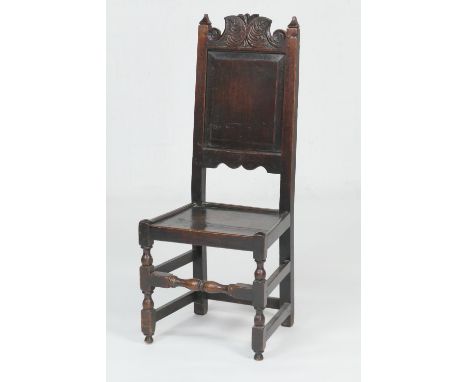 Oak joined side chair, early 18th Century, the panel back carved with an acanthus scroll top rail, solid seat, raised on turn