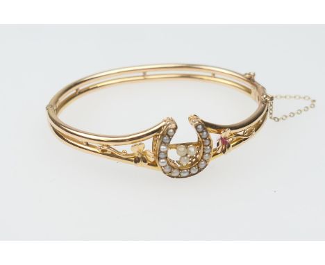 18ct gold and pearl bangle, worked with a horseshoe channel set with seed pearls and flanked with shamrock, on a double hinge