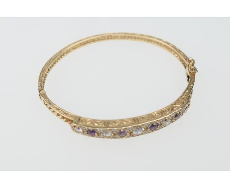 9ct gold gem set bangle, set with alternating white and ruby coloured round cut stones, graduating in size, internal diameter