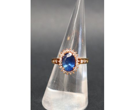 A sapphire and diamond ring, set with a central oval faceted sapphire surrounded by round brilliant cut diamonds and diamond 