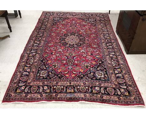 A Persian carpet, the central panel set with floral decorated medallion on a plum ground, with all-over floral design and can