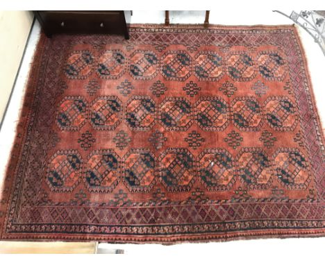 A vintage Afghan carpet, the central panel set with three rows of repeating medallions on a dark red ground, within a stepped