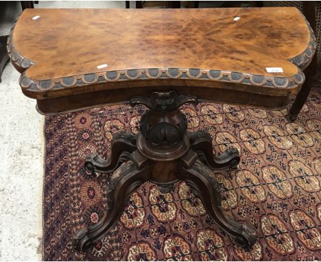 A Victorian walnut card table, the shaped top with carved edge opening to reveal a baized interior, raised on a carved pedest