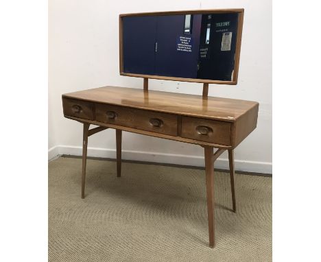An Ercol elm dressing table, the mirrored back over a shallow bow fronted table of three drawers on splayed square tapered le