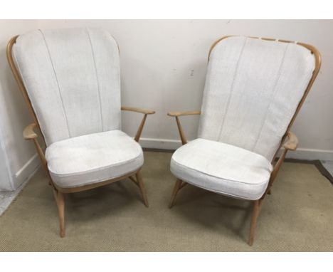 A pair of Ercol beech framed stick back arm chairs with cushioned back and seat on turned tapering legs united by stretchers,