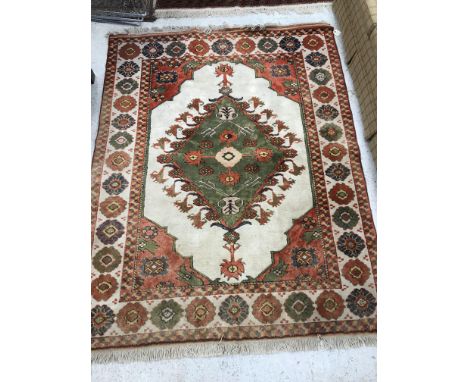 A Turkish carpet, the central panel set with green ground medallion on a cream and red floral medallion decorated ground, wit