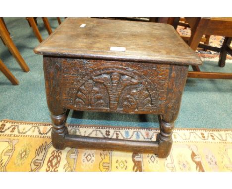 A Victorian carved oak box seat stool the lift top enclosing three baize lined pull out work trays and boxes over a lunette c