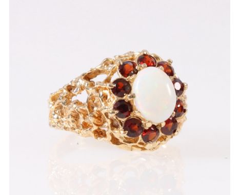 9ct yellow gold opal and ruby set ring, the central cabochon opal in claw setting, surrounded by ten faceted rubies on rustic