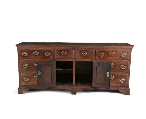 AN 18TH CENTURY OAK WELSH LOW DRESSER, the central section with twin cupboard doors below two short drawers, flanked by three
