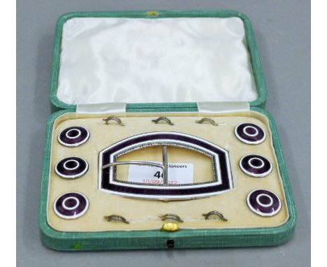 A cased set of enamel decorated silver buckle and buttons. The case 14 cm wide.