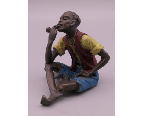 A cold painted bronze model of a boy smoking a pipe. 5.5 cm high.