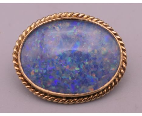 A late 20th century 9 ct gold opal doublet brooch, with rope twist surround. 2.5 cm wide. 4.6 grammes total weight.