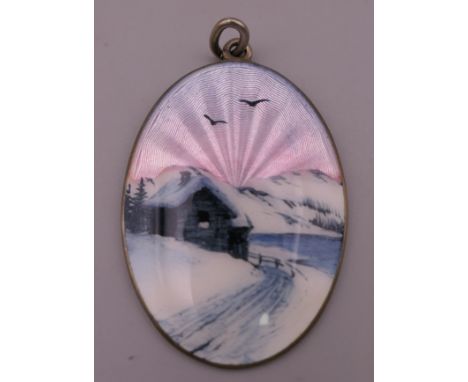 A silver and enamel pendant depicting a Scandinavian cottage in snow at sunset. 4.25 cm high.