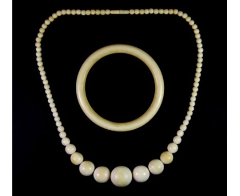 A graduated ivory bead necklace and an ivory bangle.