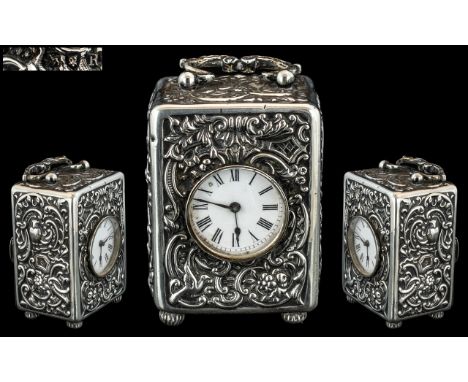A Victorian Silver Cased Miniature Clock embossed scroll floral design with birds, white porcelain dial with Roman numerals, 