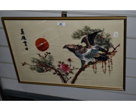A vintage Oriental embroidery on silk depicting a perched Eagle and blossoms, framed and glazed 38.5cm x 57.5cm.