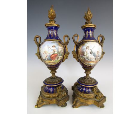 A pair of Sevres style ormolu-mounted blue-ground porcelain urns and covers, each of ovoid form with waisted neck, the cover 