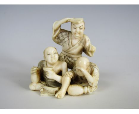 A Meiji Japanese ivory small okimono modelled as two samurai sat resting and drinking, while another stands behind them shadi