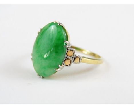 A 1930s jade dress ring, the oval cabochon stone being claw set and flanked by geometric shoulders, on an 18ct gold band 