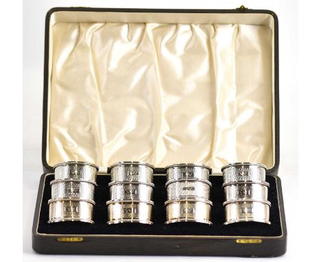 JOHN ROSE; a cased set of twelve George V hallmarked silver oval napkin rings, length 5cm, with engine turned centre and a sm
