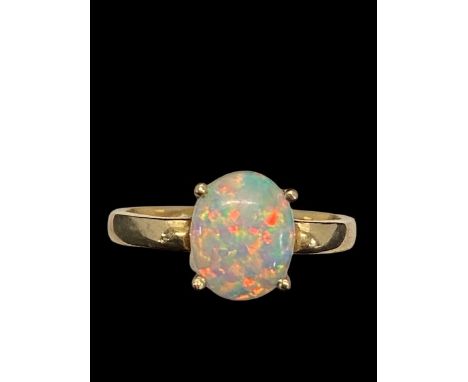 A quality white opal cabochon flashing blue, violet and red and green, solitaire ring size Q. With intergrated white stones. 
