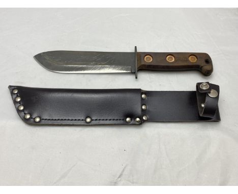 An MOD issue survival knife, steel bladed with broad arrow mark to wooden handle, in sheath. (UK postage only)