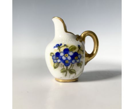 A miniature white pitcher with gold colored accents that features blue flowers painted on both sides of its center. Royal Wor