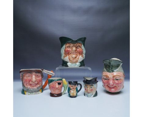 A collection of six character jugs featuring a variety of hand-painted designs with expressive faces and vibrant colors. This