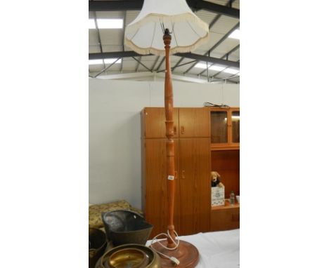 A wooden standard lamp with carved details and shade