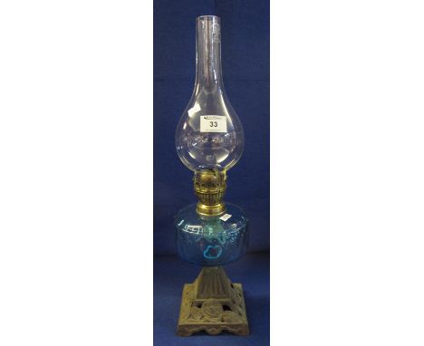Early 20th Century brass single burner oil lamp with coloured glass reservoir, pierced cast metal base and clear chimney. 53c