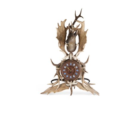 BLACK FOREST ANTLER AND WOOD MANTEL CLOCK   LATE 19TH CENTURY with various antlers and warthog tusks, surmounted by a carved 