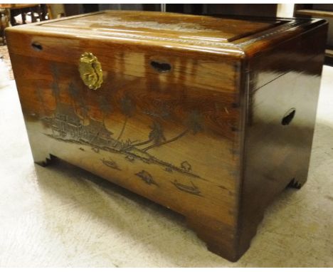 An Eastern hardwood trunk with relief carved decoration, the top opening to reveal camphor wood lined interior, together with