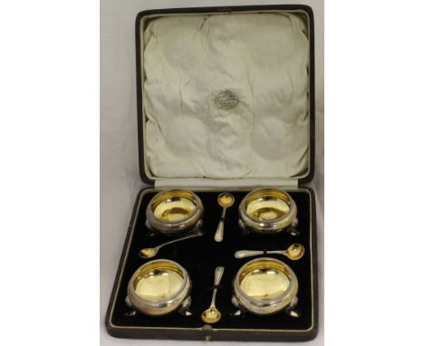 A cased set of four George V silver open salts of cauldron form with gilt-washed interiors and beaded rims, raised on three s